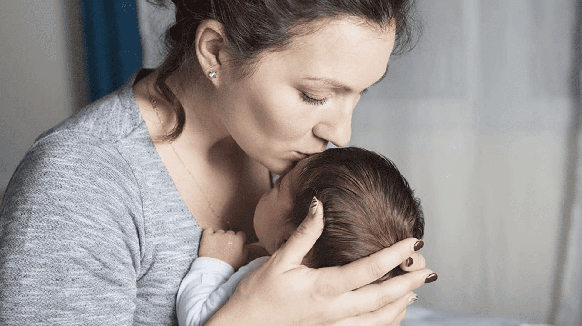 Mum kissing newborn on forehead